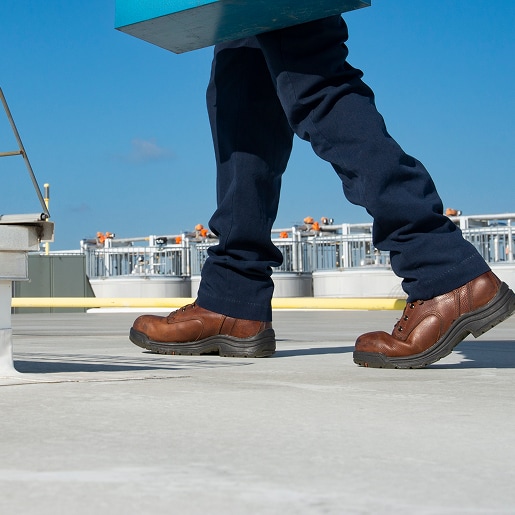Close-up of worker boots walking on a commercial roof illustrating foot traffic wear.
