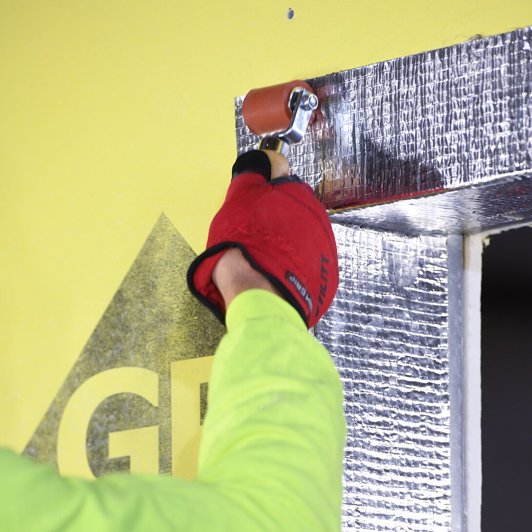Worker applying WALLcontrol aluminum butyl self-adhered flashing.