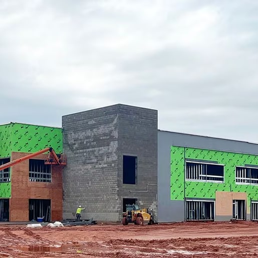 Commercial building under construction featuring green air and moisture barrier wall enclosure wrap.