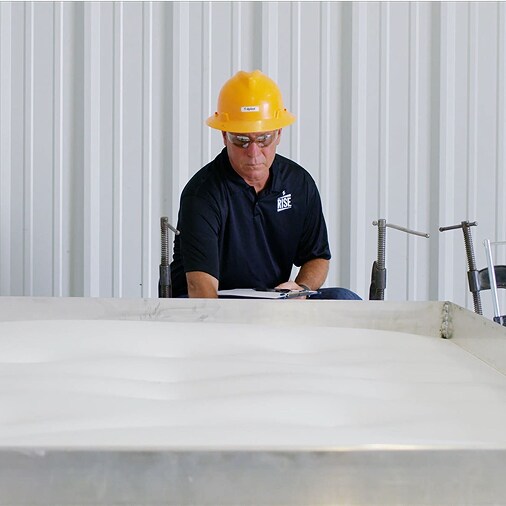 Worker in a hardhat testing a roof system, demonstrating advanced wind resistance for long-term durability and resilience.