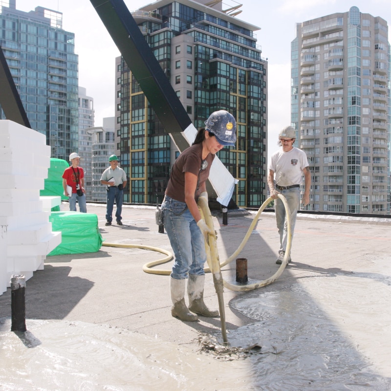 Construction workers install insulating concrete and foam on a rooftop, illustrating the Reusable Insulation Systems webinar.
