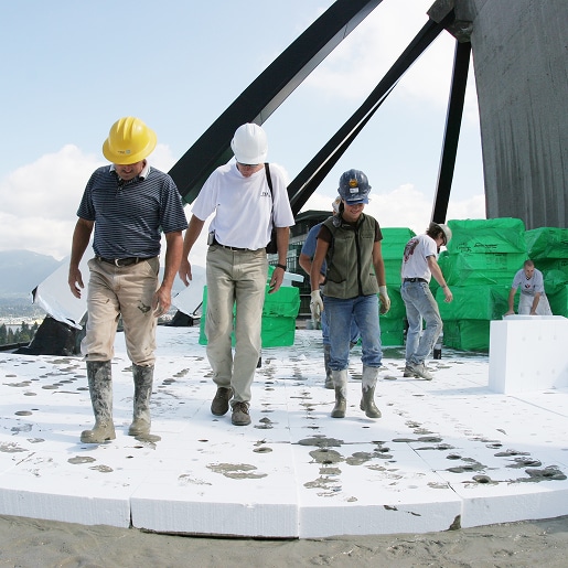 Workers walking on lightweight insulating concrete blocks during installation.
