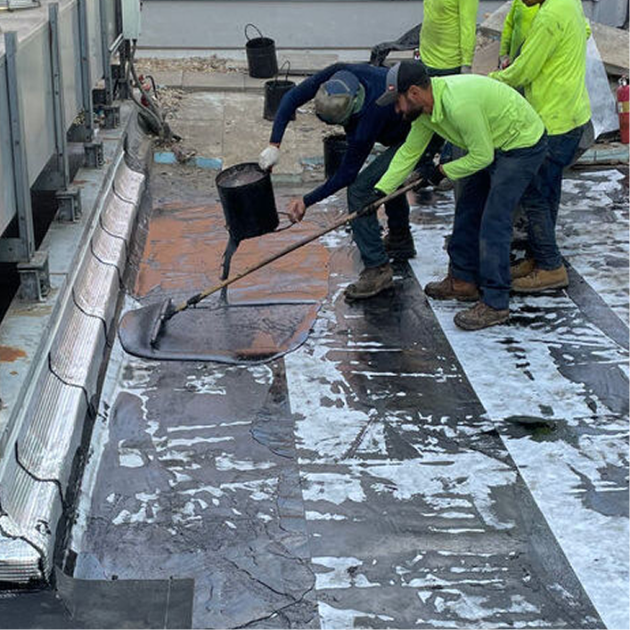 Workers apply hot-rubberized asphalt (HRA) waterproofing membrane to a commercial concrete roof deck for long-term success.