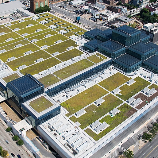 Aerial view of a commercial building with green roofing and solar panels.