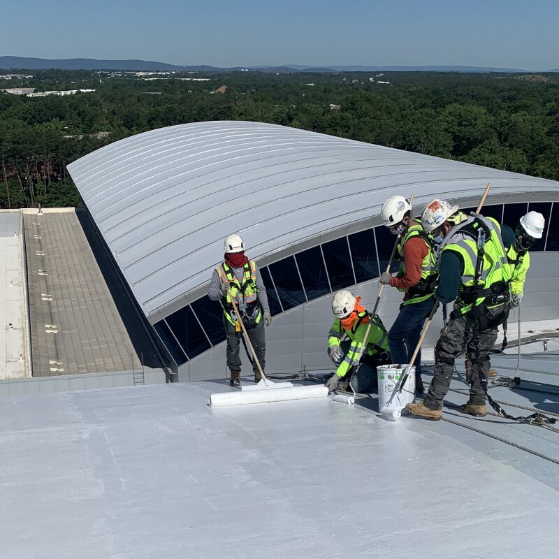 Contractors applying PMMA roofing materials on a flat roof