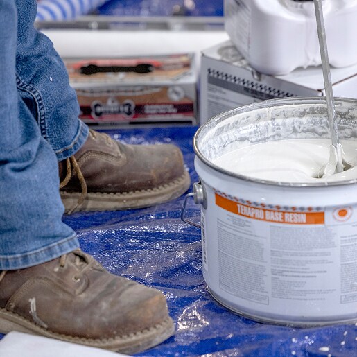 Close-up of a worker's boots next to a can of Terapro Base Resin being mixed, illustrating the Concrete Protection System Estimator.