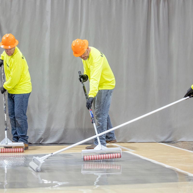 Contractors using rollers to install PMMA waterproofing resins by Siplast