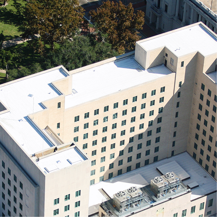 Aerial view of a commercial building featuring a white flat cool roof system with HVAC units and parapet walls.