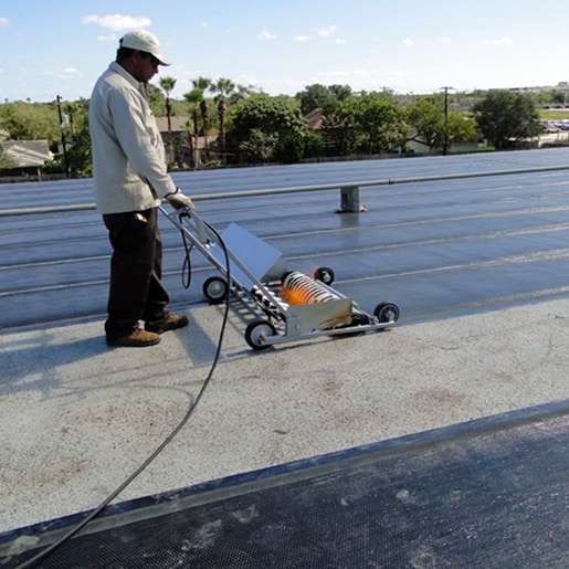 Roofer installing SBS-modified bitumen membrane using specialized application equipment.