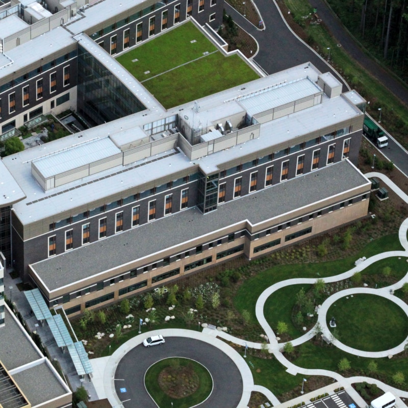 Aerial view of a large, modern building with a complex roof system integrated into the surrounding landscape