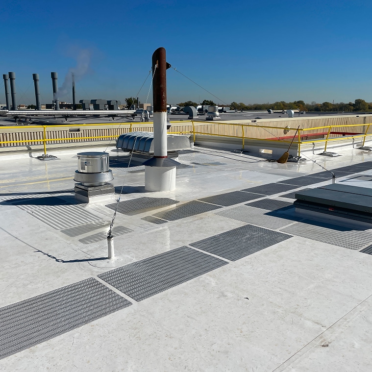 A flat commercial roof assembly is featuring a white Siplast single-ply membrane.