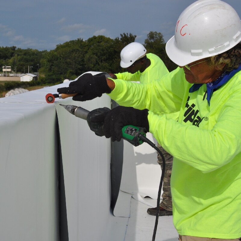 Commercial contractors welding single-ply roof materials at seams