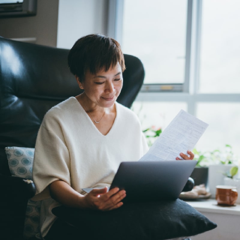 Woman reviewing financial documents on a laptop, highlighting the company 401(k) savings plan and matching.