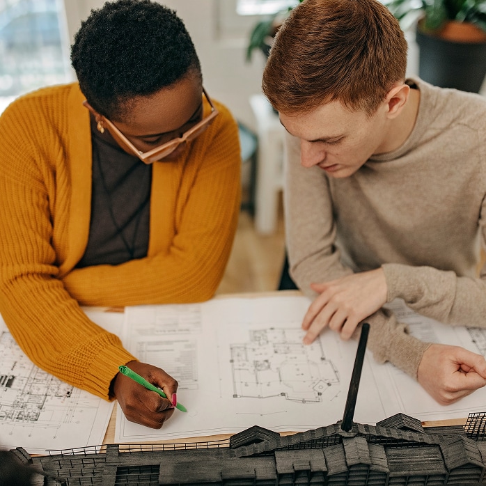 Design professionals reviewing architectural blueprints and models, representing Design Professional Resources and technical data.