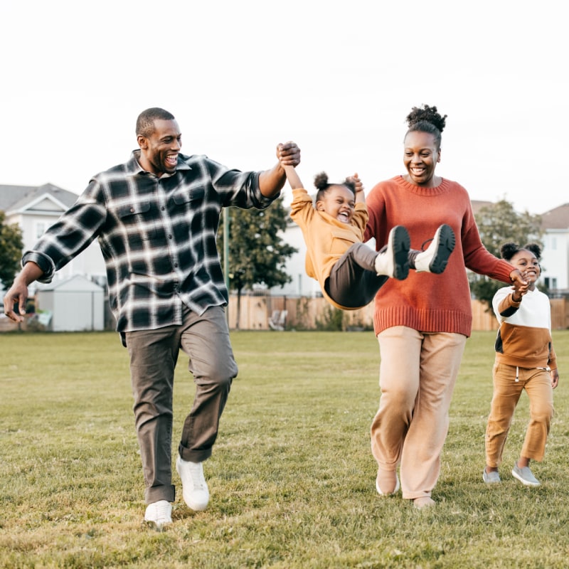 Happy family playing in a park, representing Siplast's fertility, adoption, and surrogacy benefits.