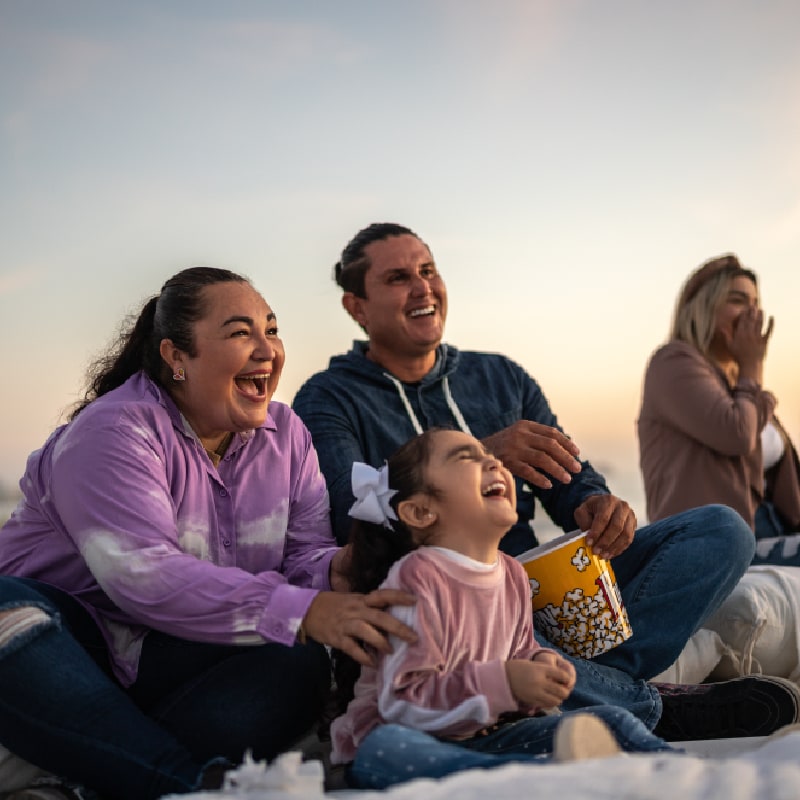 A laughing family eating popcorn together, illustrating exclusive employee discounts and lifestyle perks.