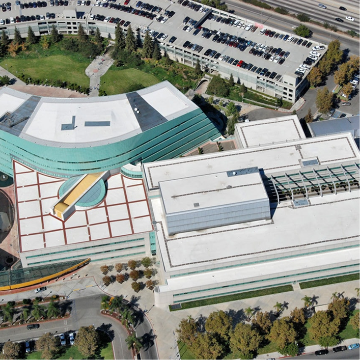 Aerial view of a complex building with multiple roof sections, illustrating LCCA Techniques for Roofs and complicated designs.