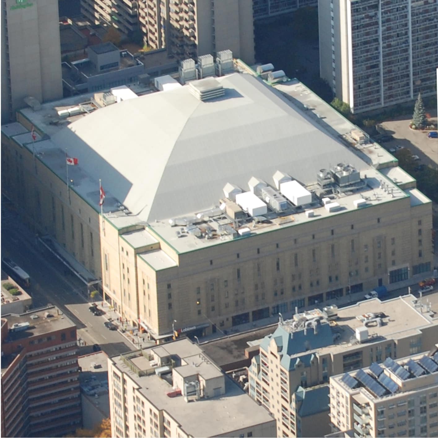 Aerial view of urban buildings, including an arena with a distinctive white roof with Siplast SBS products (Maple Leaf Gardens) surrounded by high-rise commercial structures.