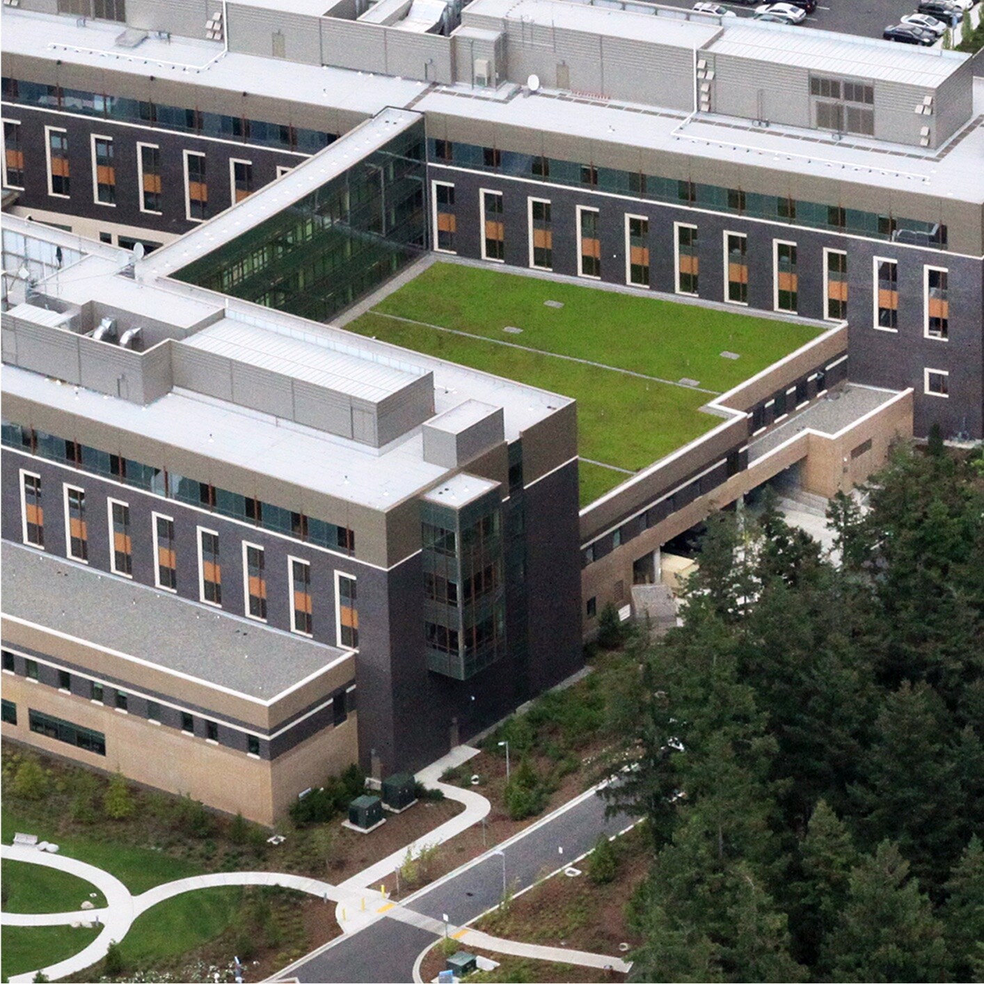 Aerial view of Swedish Hospital, a large modern medical complex with multiple wings, extensive parking, and green roofs, surrounded by trees and clear landscaping.