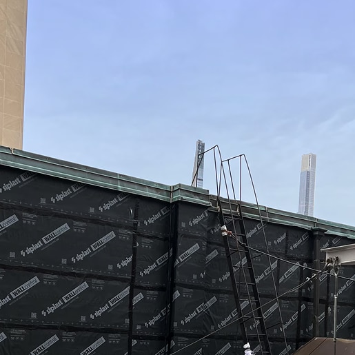 Building roof under construction with Siplast WALLcontrol air barrier and a metal ladder.