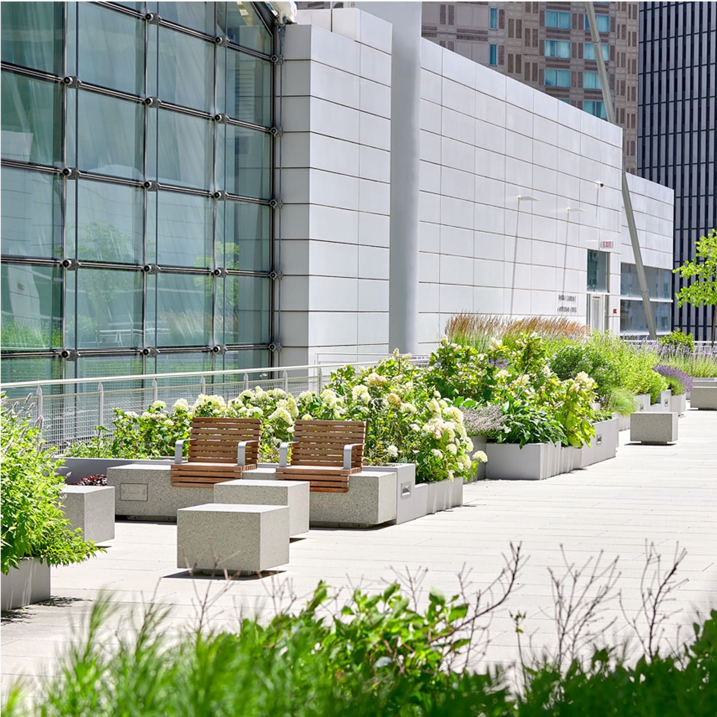Modern building with glass facade and an adjacent outdoor patio area featuring landscaped planters and benches, showcasing building aesthetics and design.