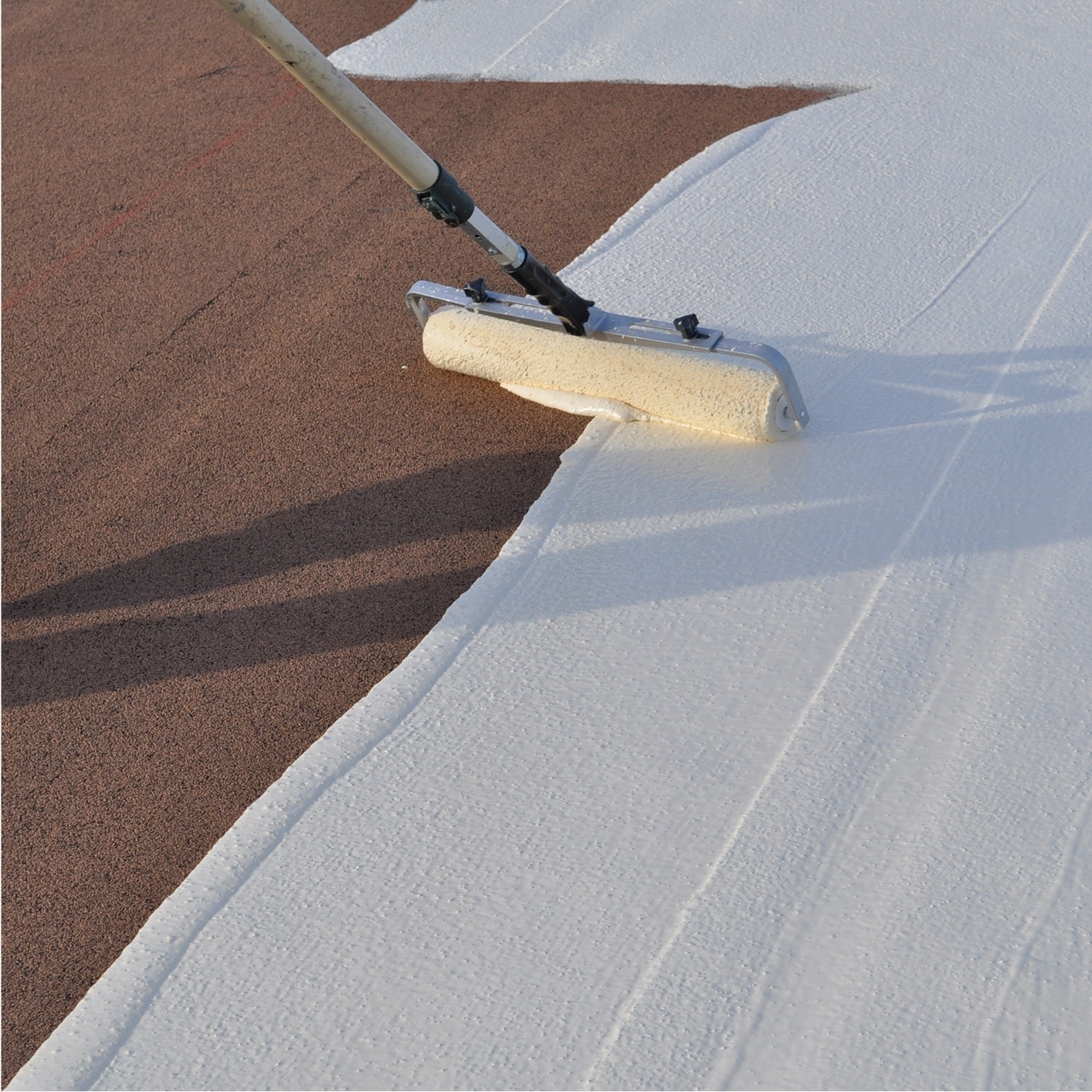 Two construction workers applying PMMA liquid waterproofing to a commercial flat roof, ensuring durable and seamless roofing.