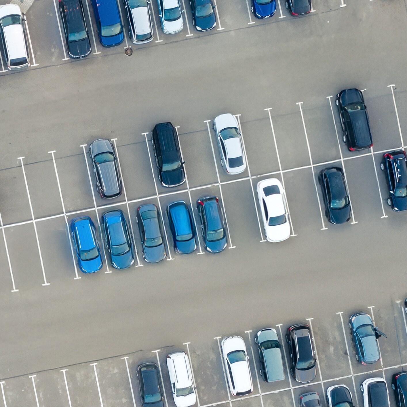 Overhead view of a large outdoor parking lot with numerous cars, indicating a PMMA application for durable surfacing.
