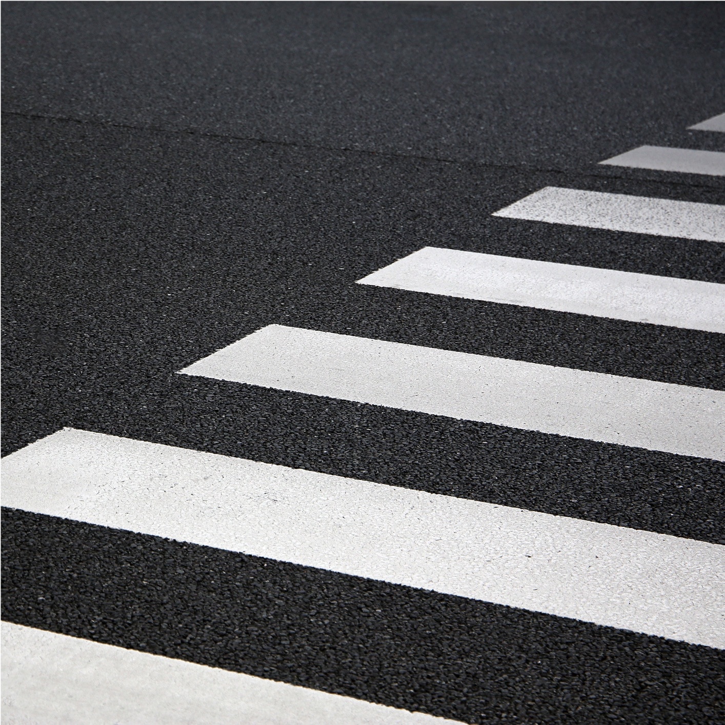 Dark industrial alleyway with a pedestrian crosswalk marked by white stripes, suitable for polyurethane and polyurea coatings for durable traffic solutions.