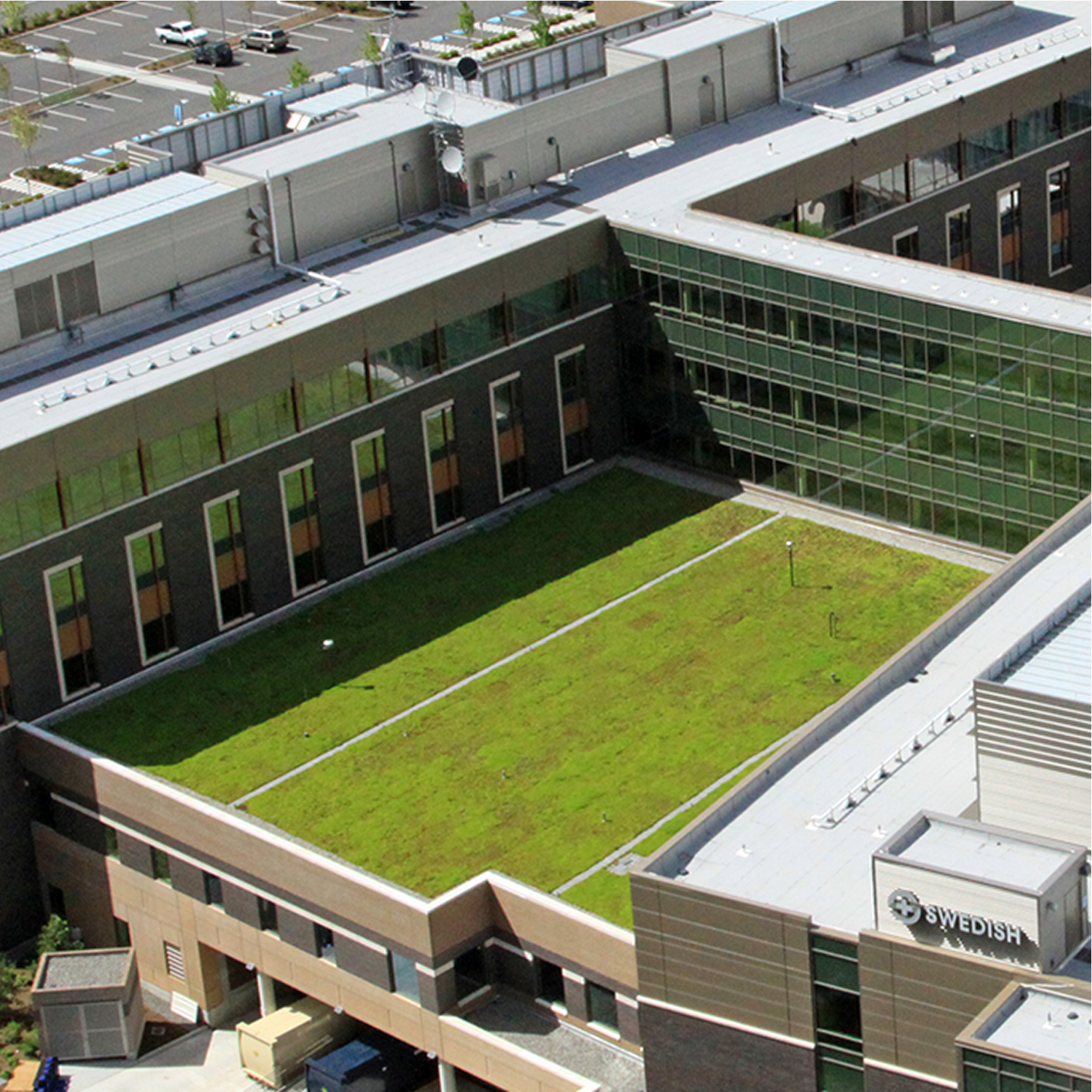 Aerial view of a modern hospital building with a large green roof section in a central courtyard.