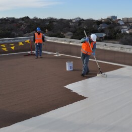 Siplast workers on roof rolling resin 