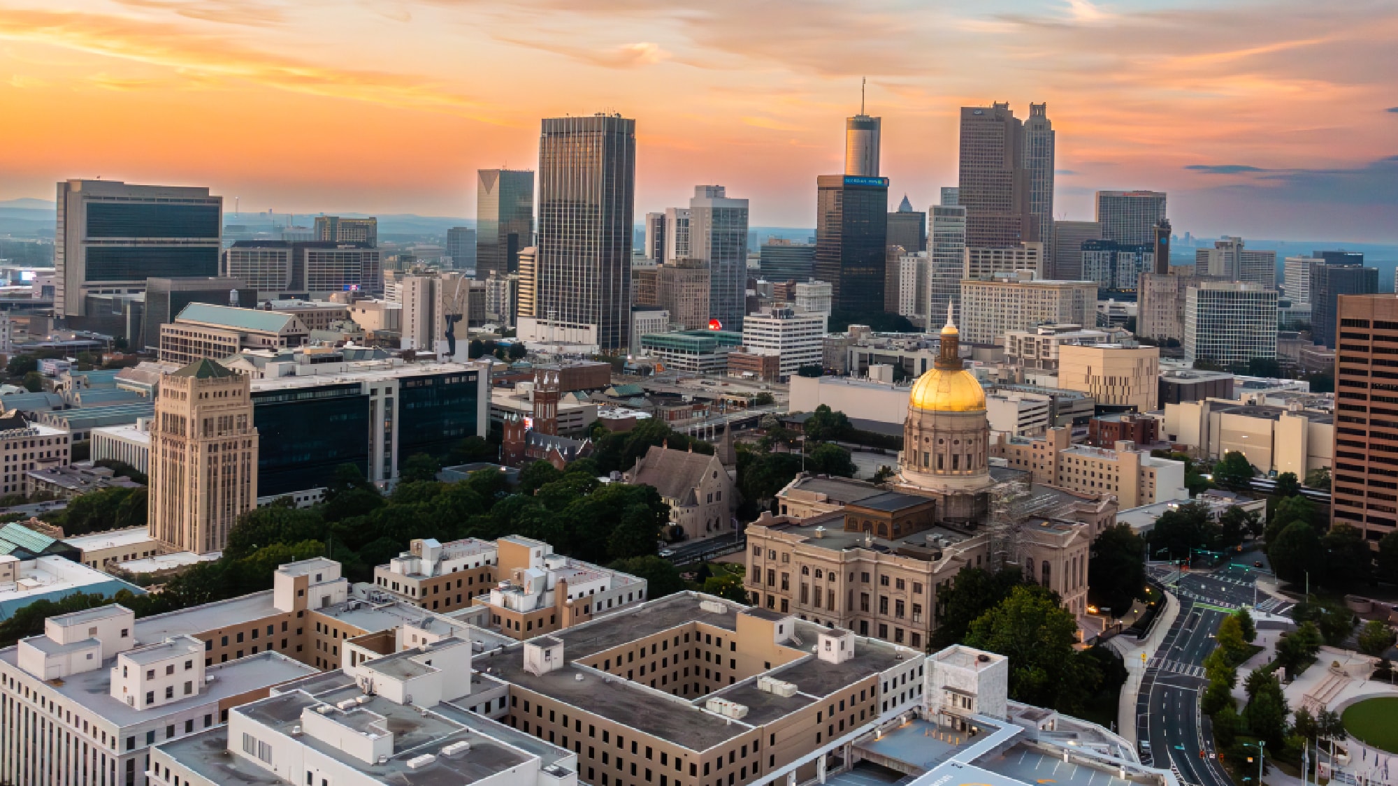 Atlanta skyline at sunset, featuring the Georgia State Capitol gold dome.