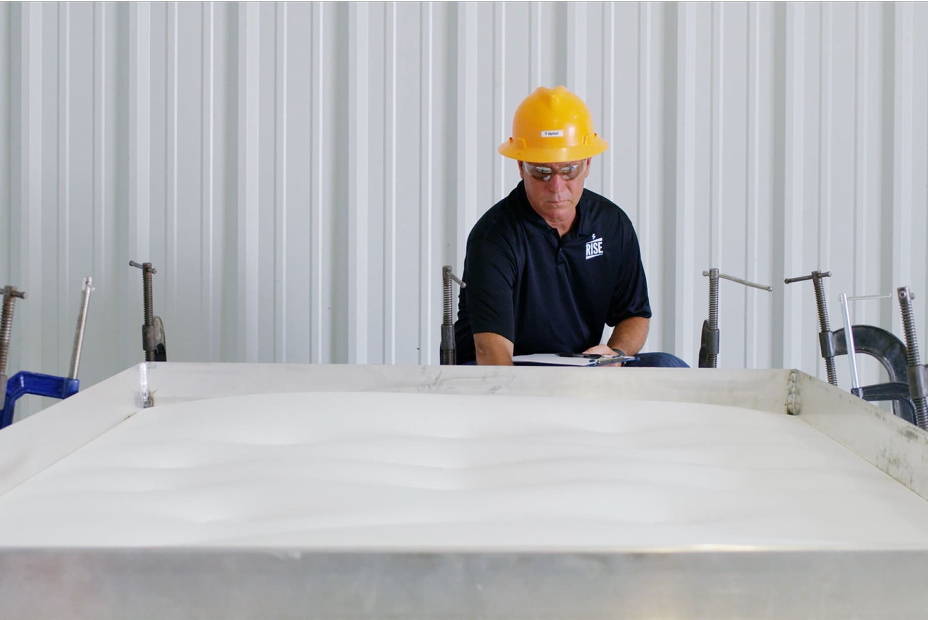 Siplast technician in a hard hat overseeing product testing at the RISE facility in Gum Springs, Arkansas, with specialized storm testing equipment.