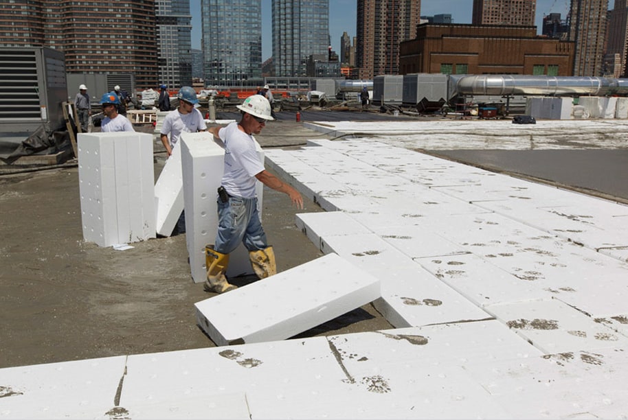Construction workers installing lightweight insulating concrete panels on a rooftop