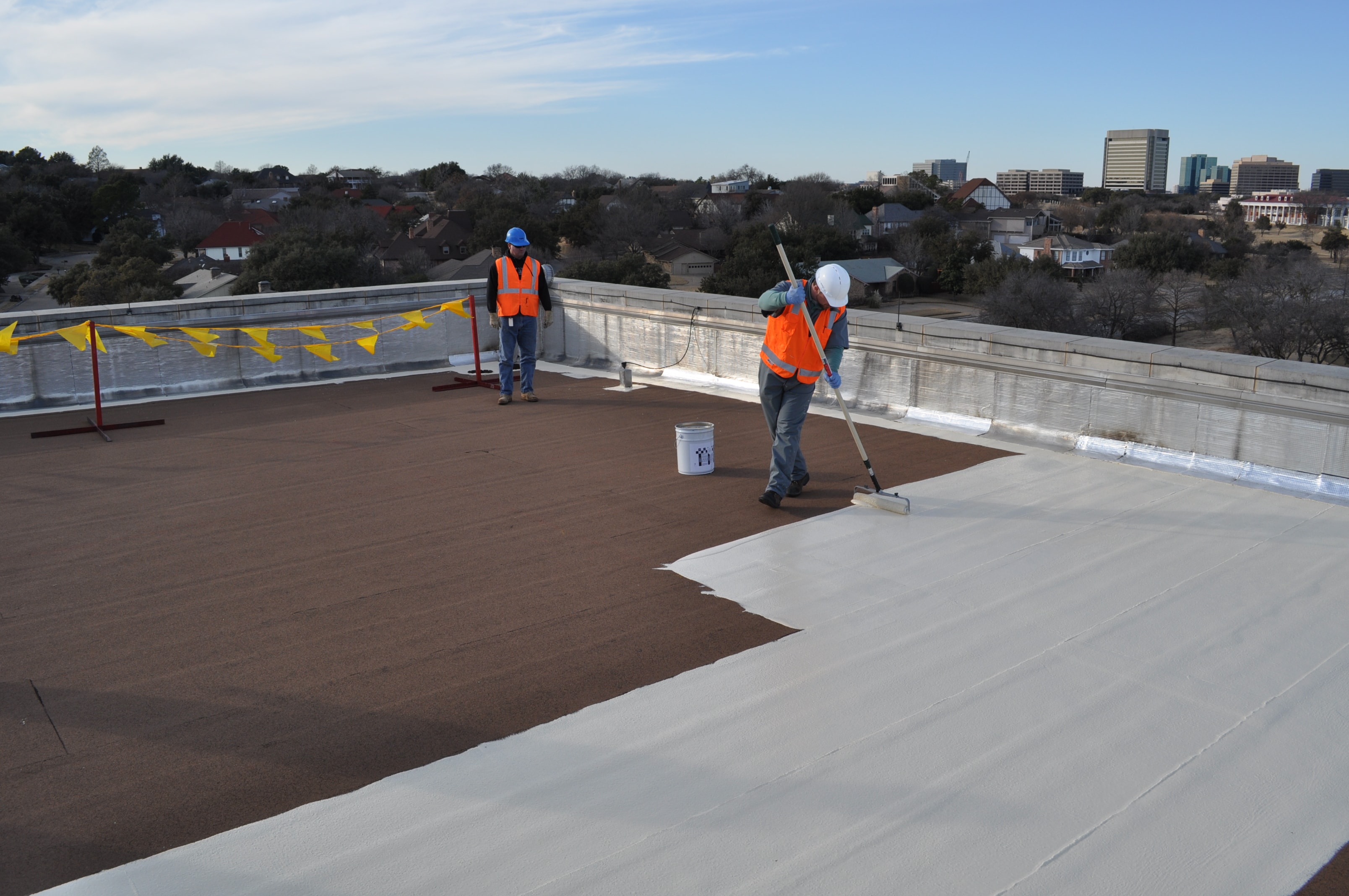 Siplast Select contractors applying white liquid-applied waterproofing membrane to a roof deck.