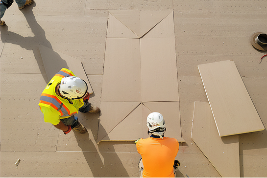 Contractors installing tapered polyiso flat roof insulation.