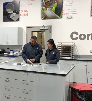 Two Siplast professionals examine materials in a laboratory, demonstrating dedication to technical content and advancements in building enclosure.