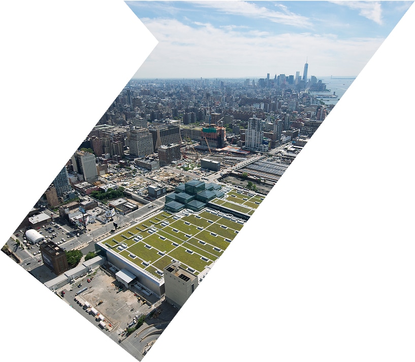 Aerial view of a city with a mix of high-rise and low-rise buildings, and a green space visible on a rooftop