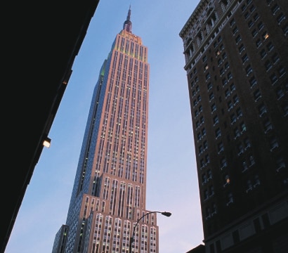 A low-angle view of a skyscraper, framed by two other tall buildings on either side, against a clear sky