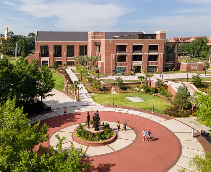 Aerial view of the Student Union building Florida State University campus, landscaped paths, and a round plaza featuring a statue and people walking nearby