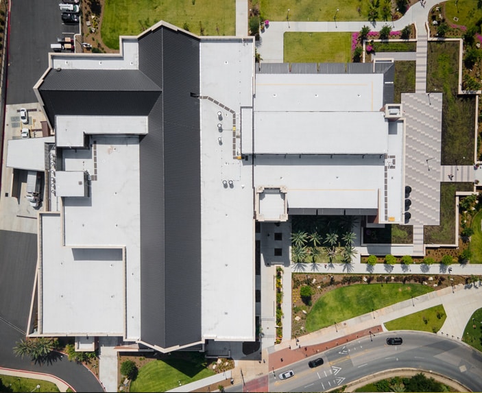 Aerial view of the Student Union building at Florida State University with a Siplast roof, surrounded by green lawns, pathways, and parked cars, conveying a structured, urban tone.
