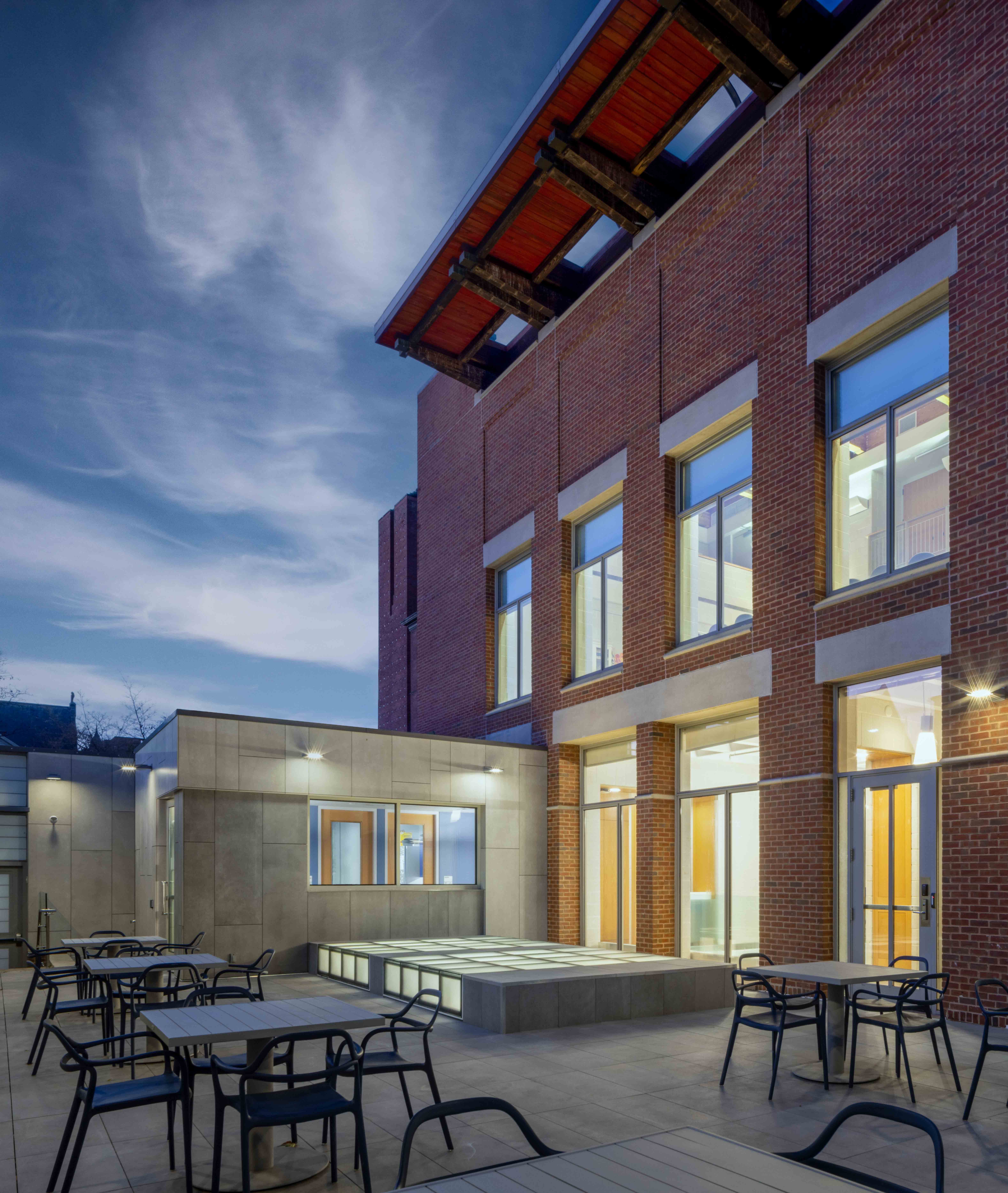 Joseph Slifka Center for Jewish Life at Yale exterior with a modern brick facade, large windows, and outdoor seating area, illuminated during twilight.