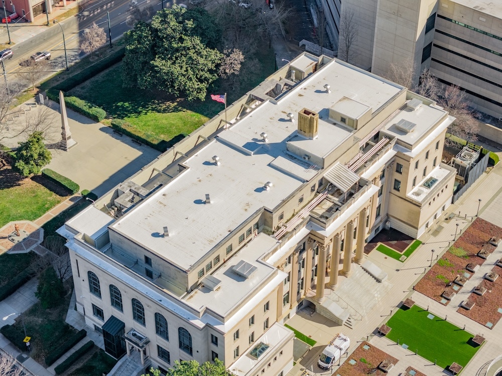 Top-down view of a multi-level civic structure highlighting the complex rooftop layout and surrounding urban park space.