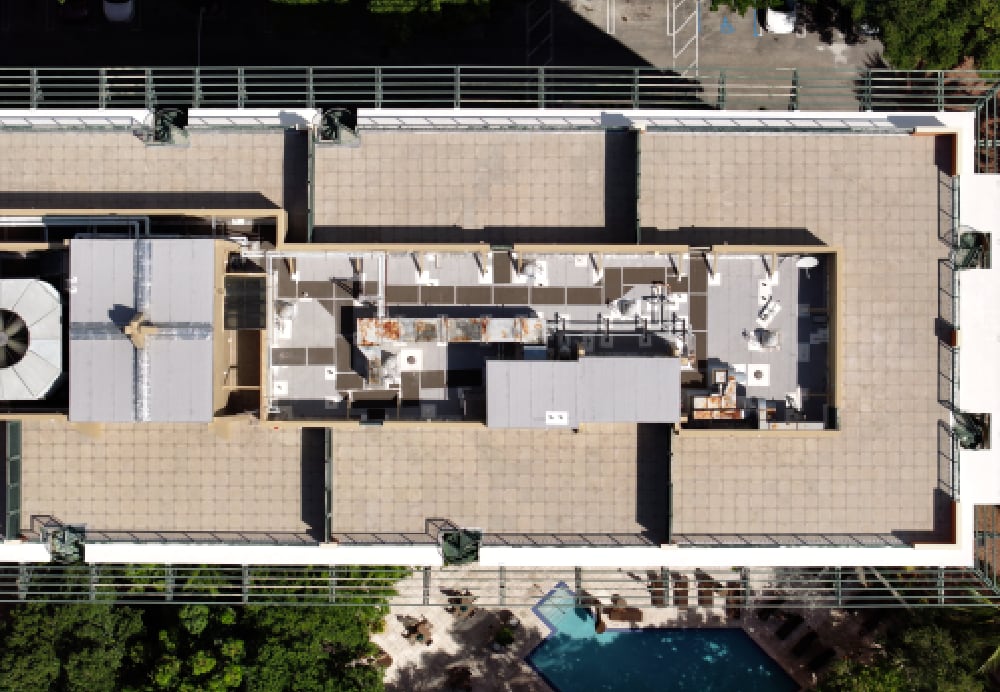 Direct overhead drone shot of the hotel's roof deck and mechanical areas, highlighting the clean installation of pavers and waterproofing layers.