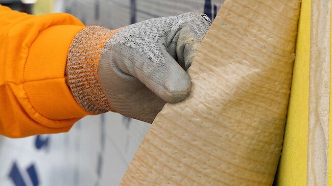 Close-up of a contractor peeling the release liner from a Siplast self-adhered wall membrane.