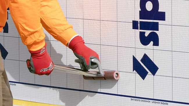 Contractor using a weighted roller to ensure proper adhesion of a WALLcontrol SA 40 VR membrane.