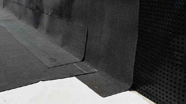 Close-up of a black TeraPROOF™ protection course being installed over a waterproofing membrane.