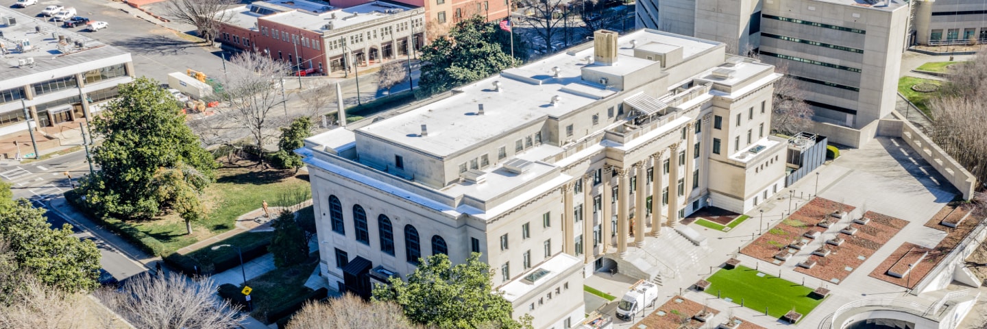 Wide architectural shot of the District Attorney’s Office exterior, highlighting the white stone facade and symmetrical rows of windows under a clear sky.