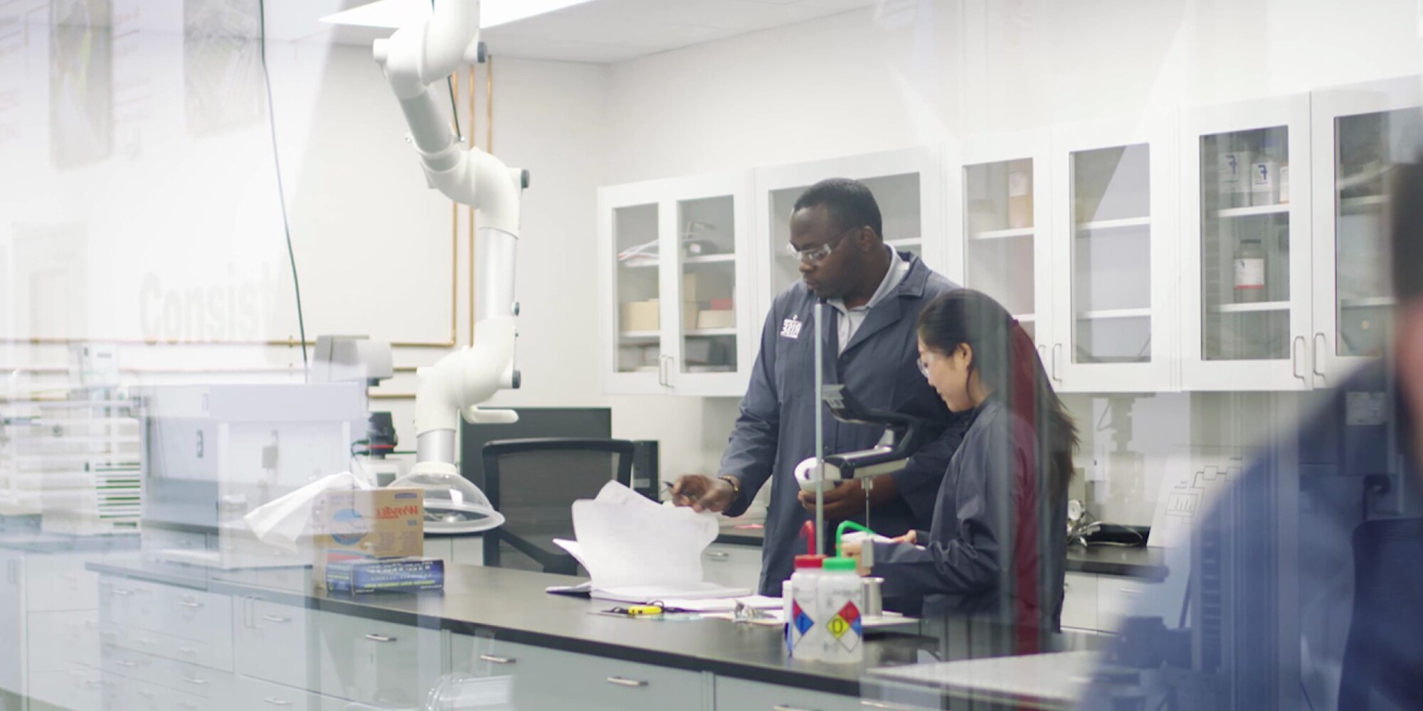 RISE Lab staff reviewing technical data and documents at a lab bench with bright white cabinets and safety equipment.