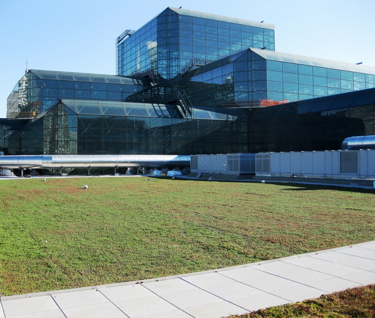 Modern convention center with a large green roof blending into the urban landscape