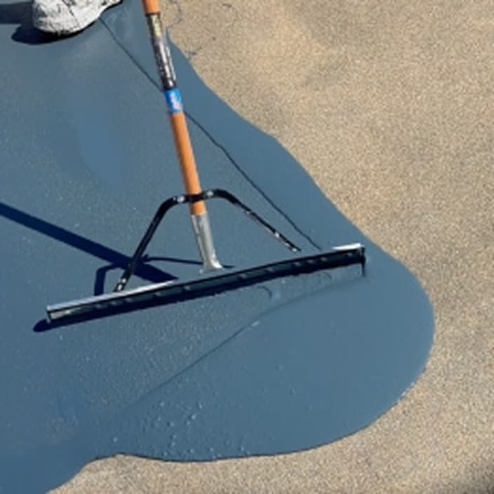 Squeegee spreading Siplast Terapro PUR liquid-applied resin for pedestrian and vehicular deck coating applications.
